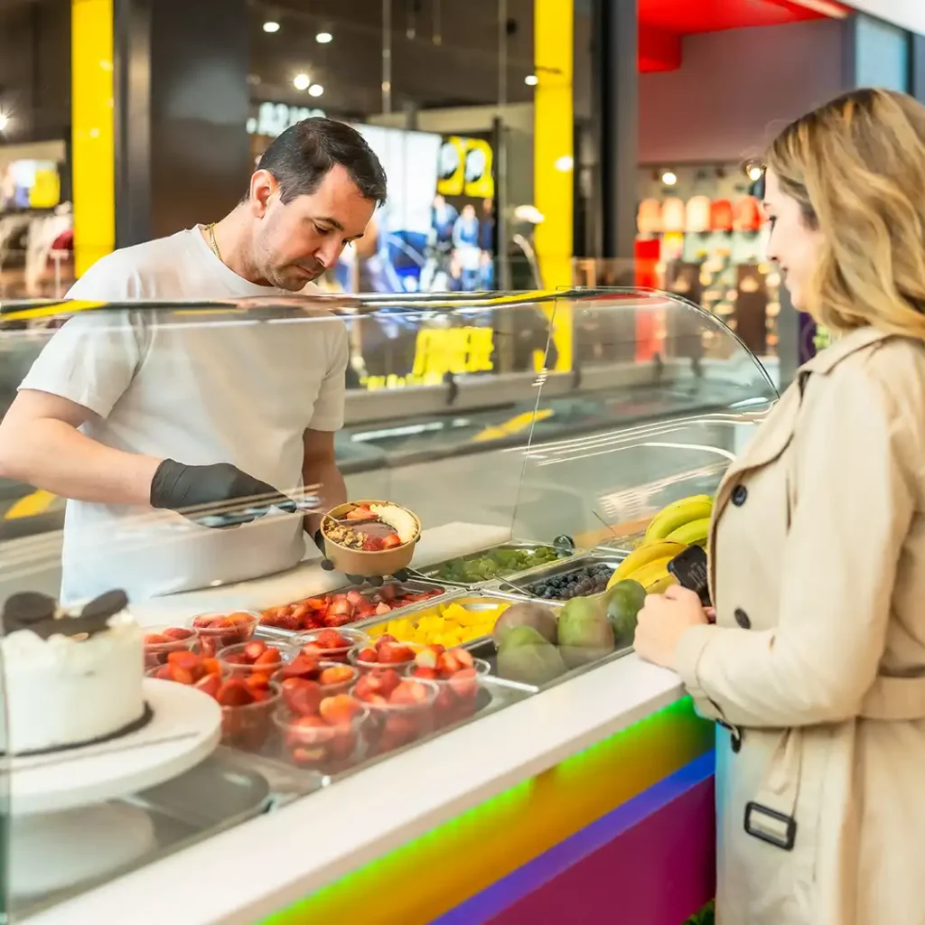 Customer ordering a fresh fruit bowl at a shopping centre food court counter
